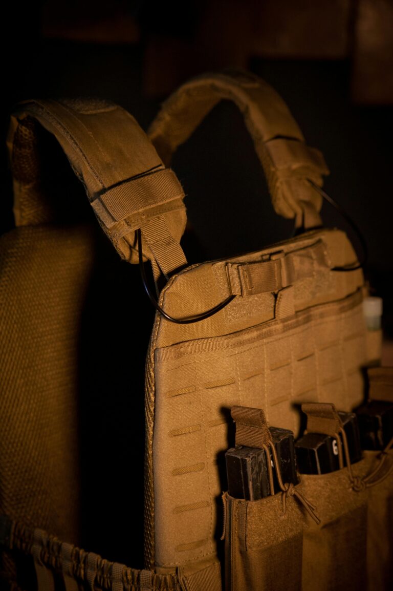 Close-up of a tactical military vest with multiple magazine pouches in low light.
